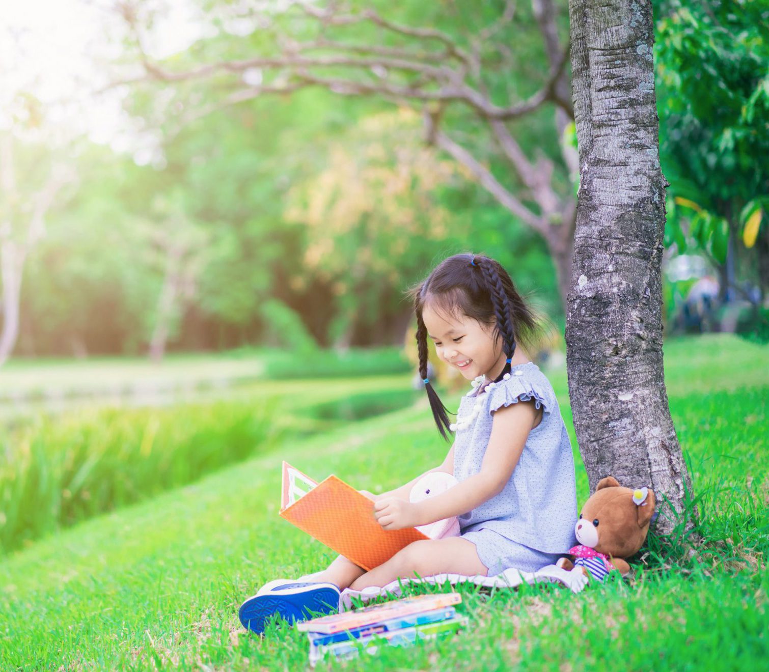 child sitting under a tree reading a book